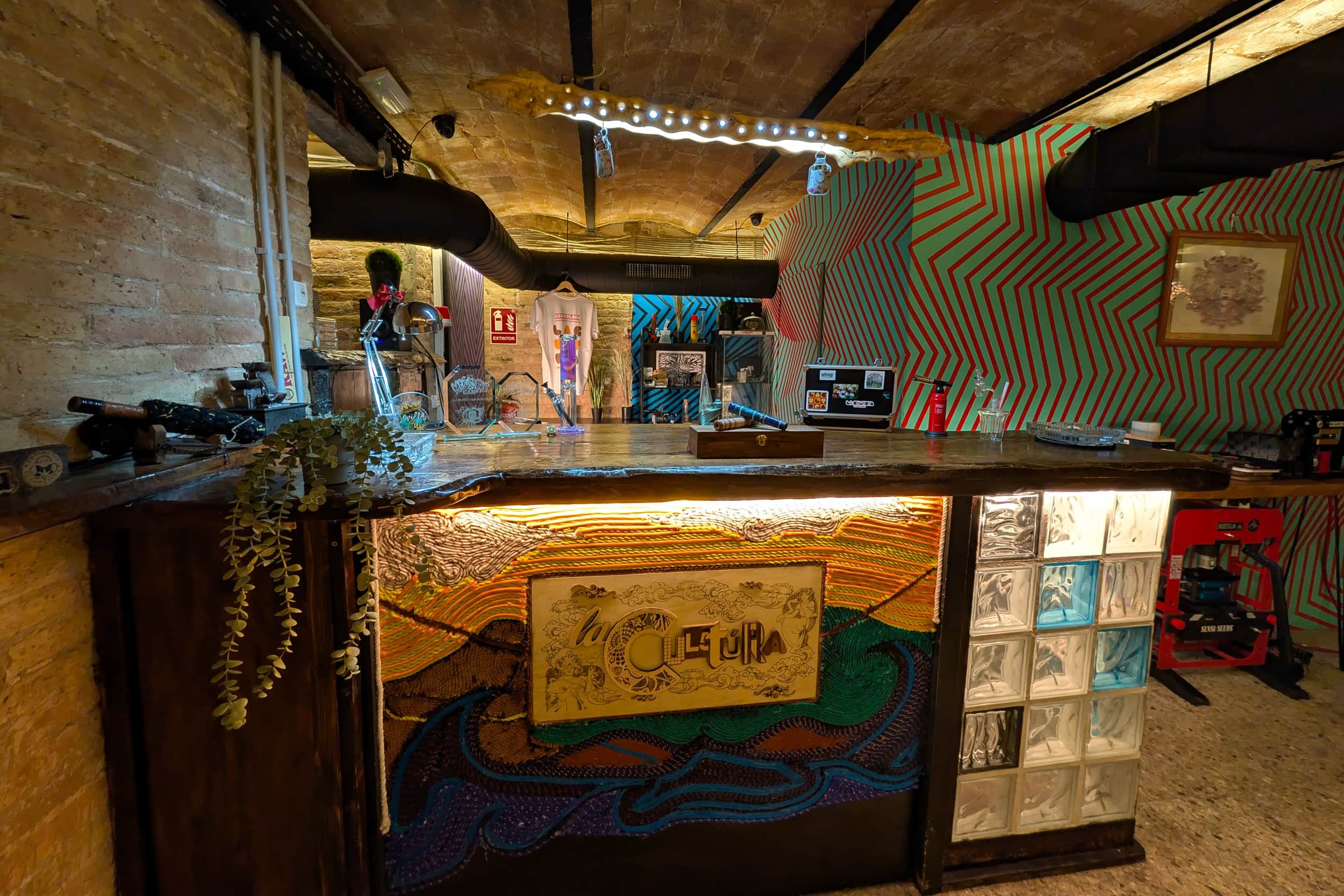 Barbereich des cannabis-clubs La Cultura mit künstlerischer Theke und lebendiger Wandgestaltung in Barcelona